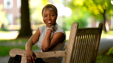 Marie Victoire Alexis sits on a bench on campus and smiles.