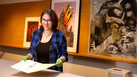 Hannah Kosko wears gloves as she holds a print in the Samek Art Museum.
