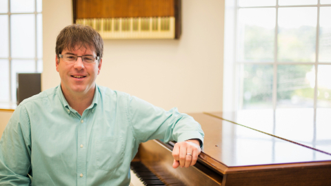 Ryan Malone sits with his elbow propped up on the edge of an organ.