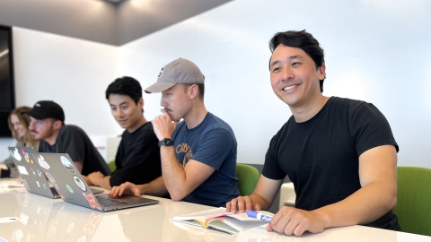 Alumni Brian Pei at his office sitting next to co-workers.