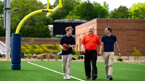 Professors Sam Gutekunst (right) and  Joe Wilck (center) discuss an NFL-related research project with student Max Wilson '27 (left)