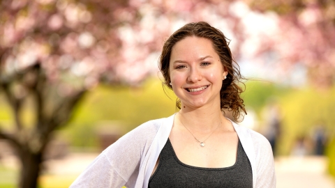 Grace Ginder ’25 stands outside with cherry blossom trees in the background.