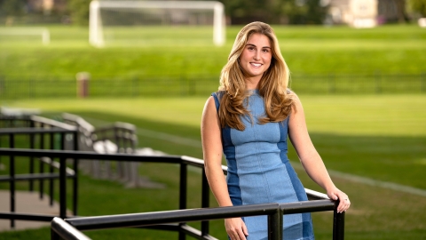 Lea Tarzy &#039;24 poses in a blue dress in the stands of a soccer field.