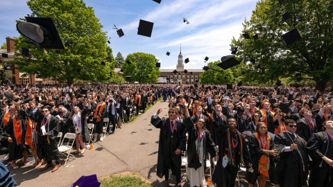 Graduates throw their caps into the air while standing outside