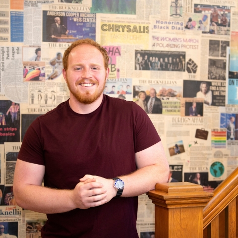 Jaxon White poses in front of a wall of newspaper clippings