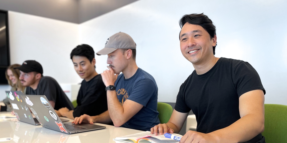 Alumni Brian Pei at his office sitting next to co-workers.