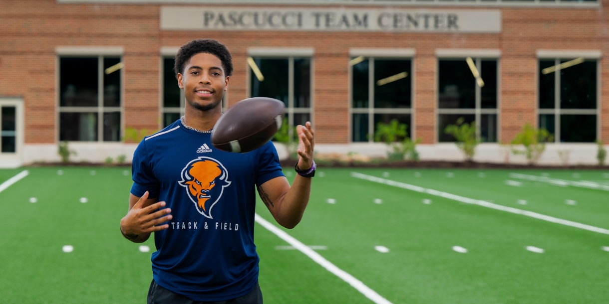 Chris Sims tossing a football on the field.