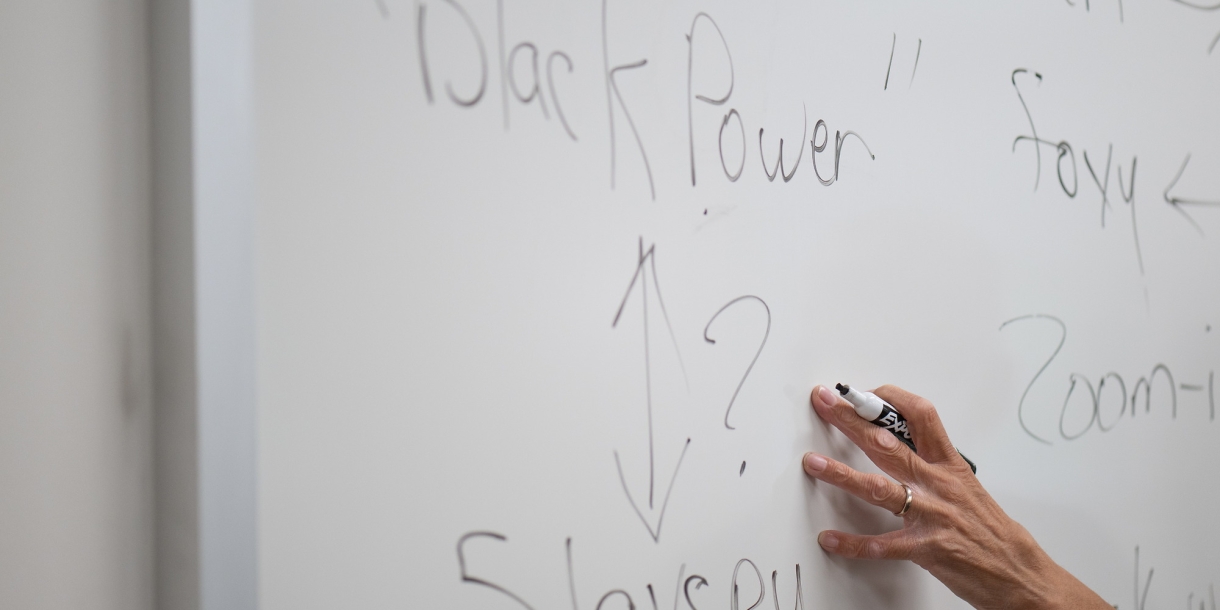 A hand writes Black Power on a whiteboard