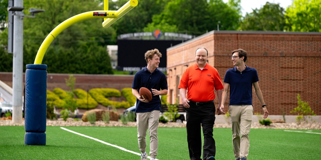 Professors Sam Gutekunst (right) and  Joe Wilck (center) discuss an NFL-related research project with student Max Wilson '27 (left)