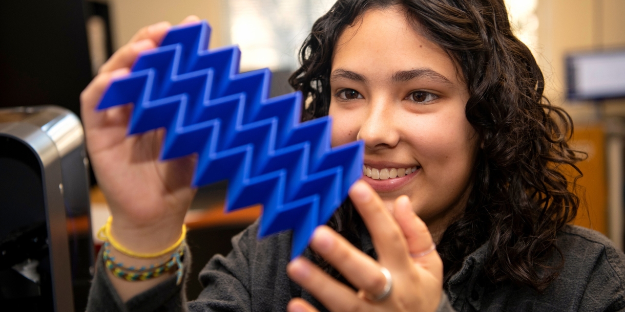 Iona Pitkin '25 looks at a plastic plate with 3D zig-zag design.