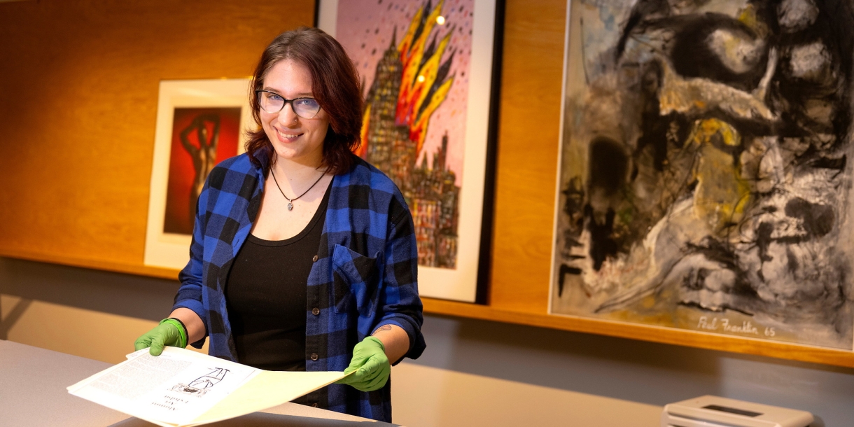 Hannah Kosko wears gloves as she holds a print in the Samek Art Museum.