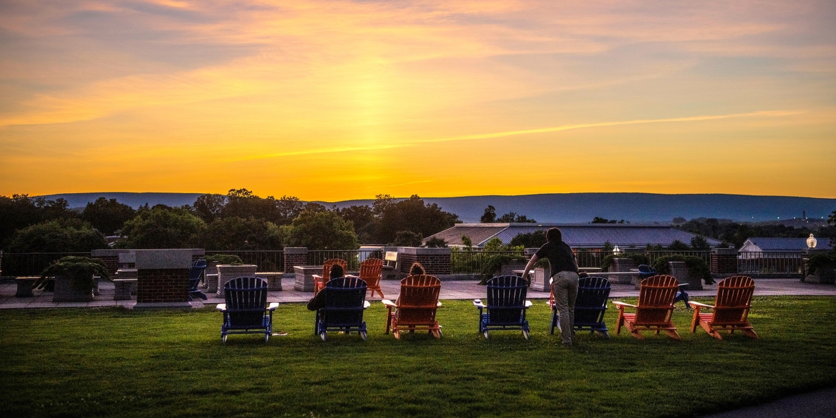 Students watch the sunset sitting on Adirondack chairs on Malesardi Quad