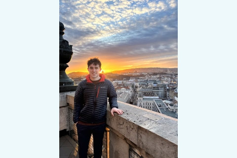 Alejandro Vargas-Altamirano ’25 stands above a city while the sun sets in the background.