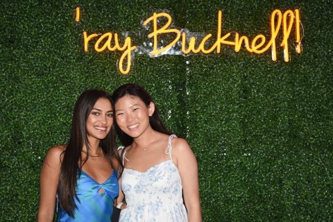 Young alumni pose in front of a &quot;&#039;ray  Bucknell&quot; neon sign.