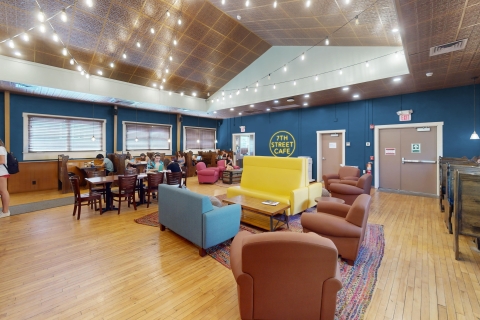 Colorful chairs fill the interior seating area at the 7th Street Cafe. Booths line the walls. String lights illuminate the pressed tin ceiling.
