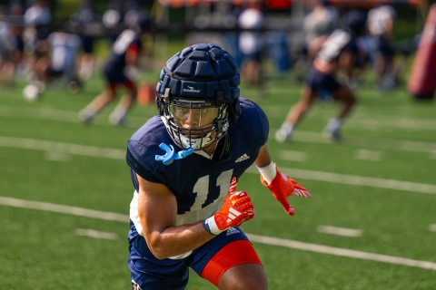 Chris Sims in a football helmet and uniform on a turf field.