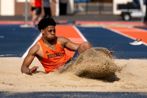 Chris Sims lands in a sand pit after performing a triple jump.