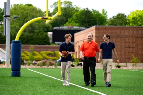 Professors Sam Gutekunst (right) and Joe Wilck (center) discuss an NFL-related research project with student Max Wilson '27 (left)