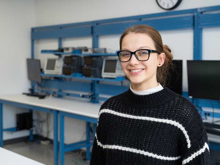 Breenah Kennedy ’26 stands in a classroom with computers in the background. 