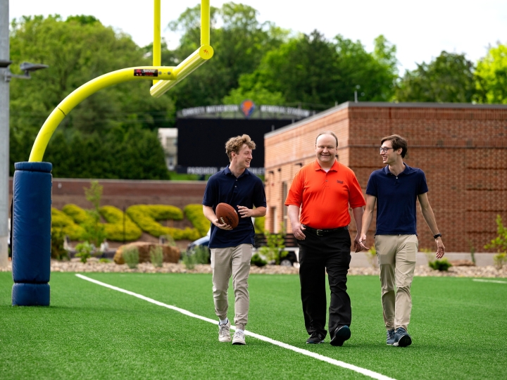 Professors Sam Gutekunst (right) and  Joe Wilck (center) discuss an NFL-related research project with student Max Wilson '27 (left)