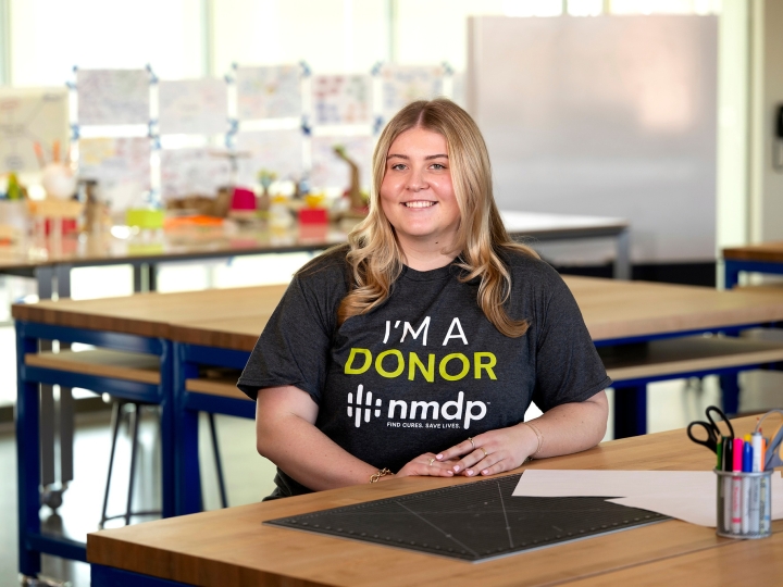 Kate Ellis '25 sits at a desk in a classroom wearing an "I'm a Donor T-shirt."