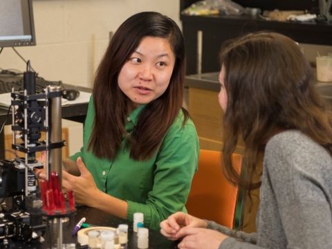 Professor JiaJia Dong talking to a student about an optical tweezer