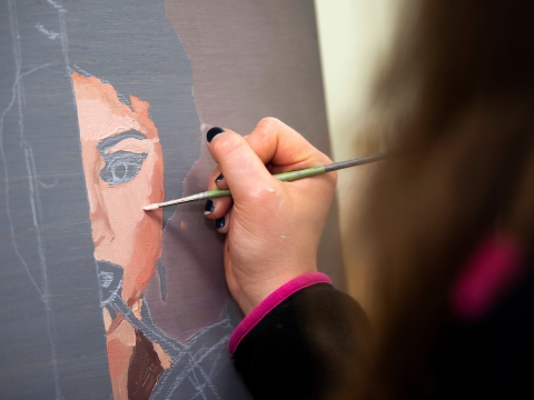 A painter meticulously creating a face on canvas