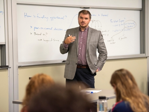 Professor lecturing in front of whiteboard