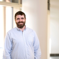 Portrait of Professor Greg O'Neill standing in a well lit hallway